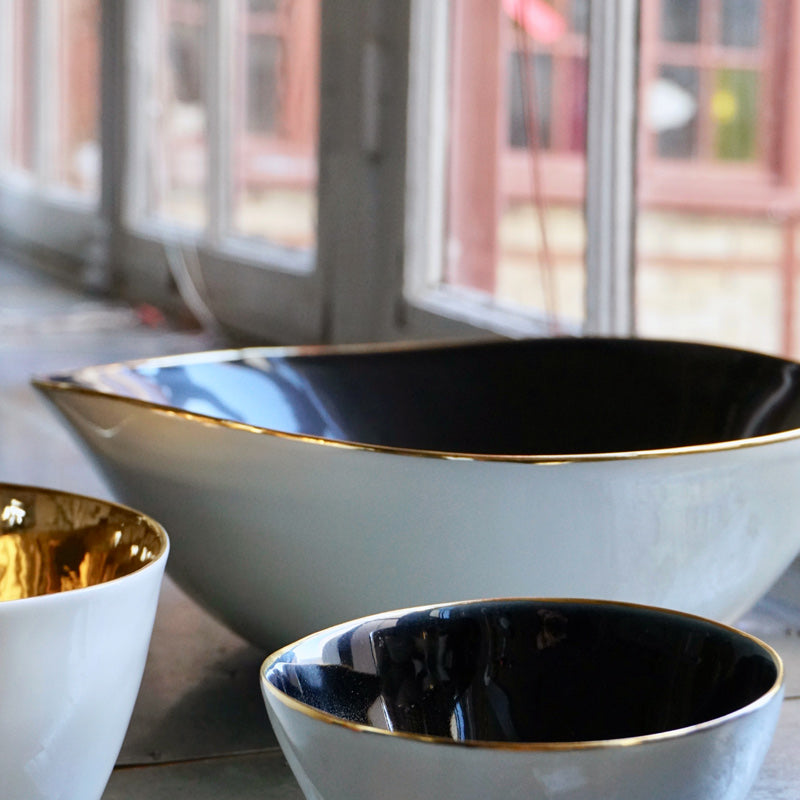 gros plan sur des saladiers en porcelaine avec interieur noir et bordure or