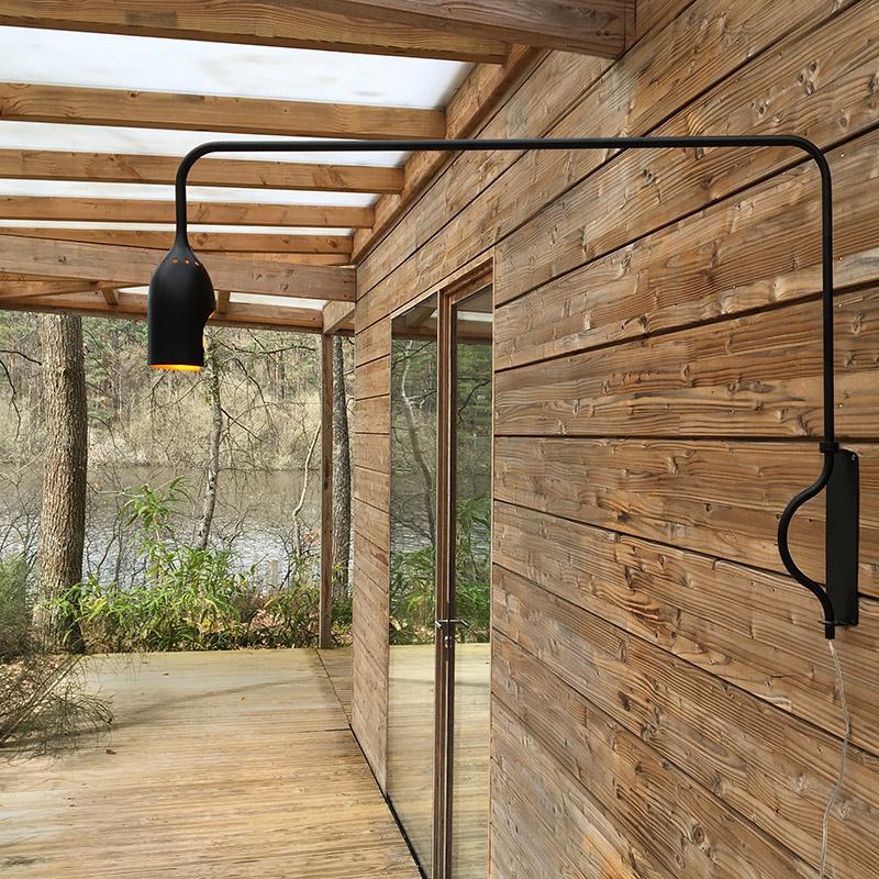 grande lampe en aluminium laqué noir fixée sur un mur extérieur en bois - tsé tsé