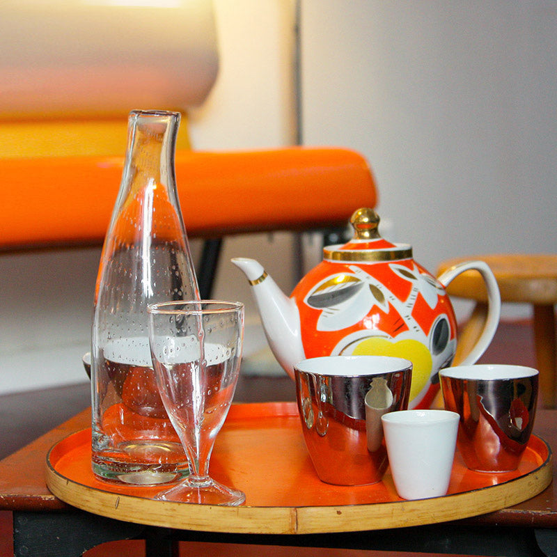 carafe et verre à pied en verre incrusté de petites bulles sur un plateau rond orange - tsé tsé