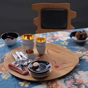 Plateau en bois avec vaisselle, posés sur une table avec nappe fleurie.