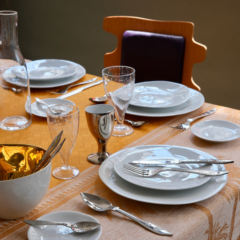 Repas avec vaisselle de fête et couverts à motifs poinconnés.