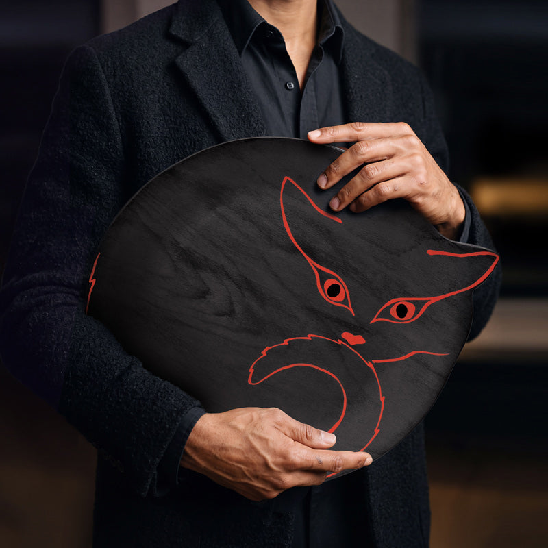 Plateau en bois noir avec silhouette de chat orange vif, tenu par une homme