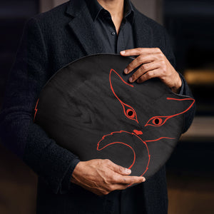 Plateau en bois noir avec silhouette de chat orange vif, tenu par une homme