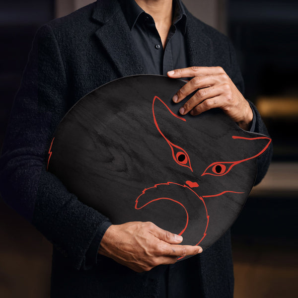 Plateau en bois noir avec silhouette de chat orange vif, tenu par une homme