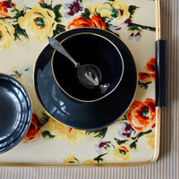 bol et assiette noir et or vue de dessus sur un plateau à fleur