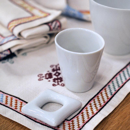petit coquetier carré en porcelaine blanche sur une nappe brodée - tsé tsé
