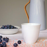 tasse à thé en porcelaine de forme irrégulière avec des myrtilles en arrière-plan - tsé tsé
