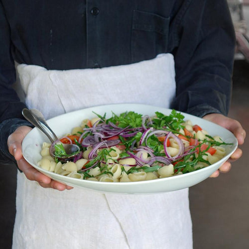 salade de pâtes colorée dans un grand plat bas en porcelaine tenu en main - tsé tsé