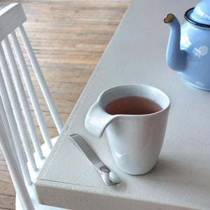 tasse à anse en porcelaine blanche posée sur la tale - tsé tsé